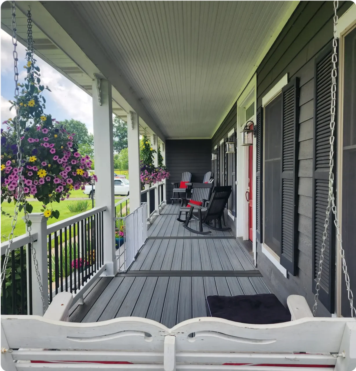 Inviting front porch with swing and hanging flowers, offering a relaxing outdoor space.