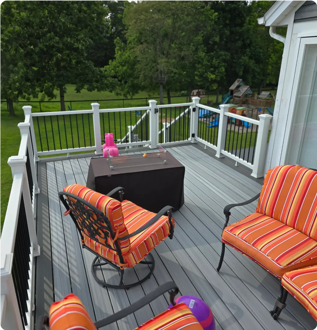Custom deck with comfortable striped chairs and glass table, perfect for outdoor relaxation.