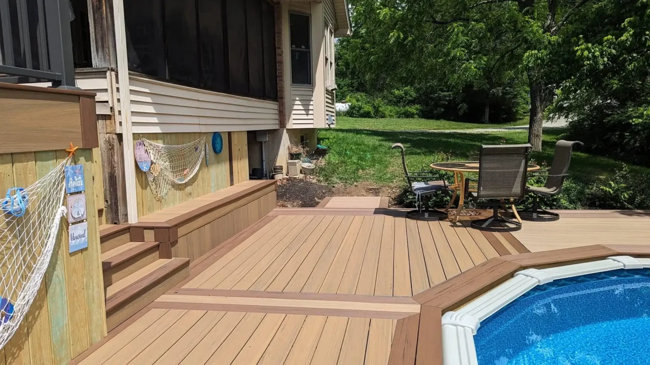 View of the pool deck showing TimberTech Terrain composite decking, built-in bench seating, and the skirting with fishing nets. A seating area and pool are visible in the foreground.