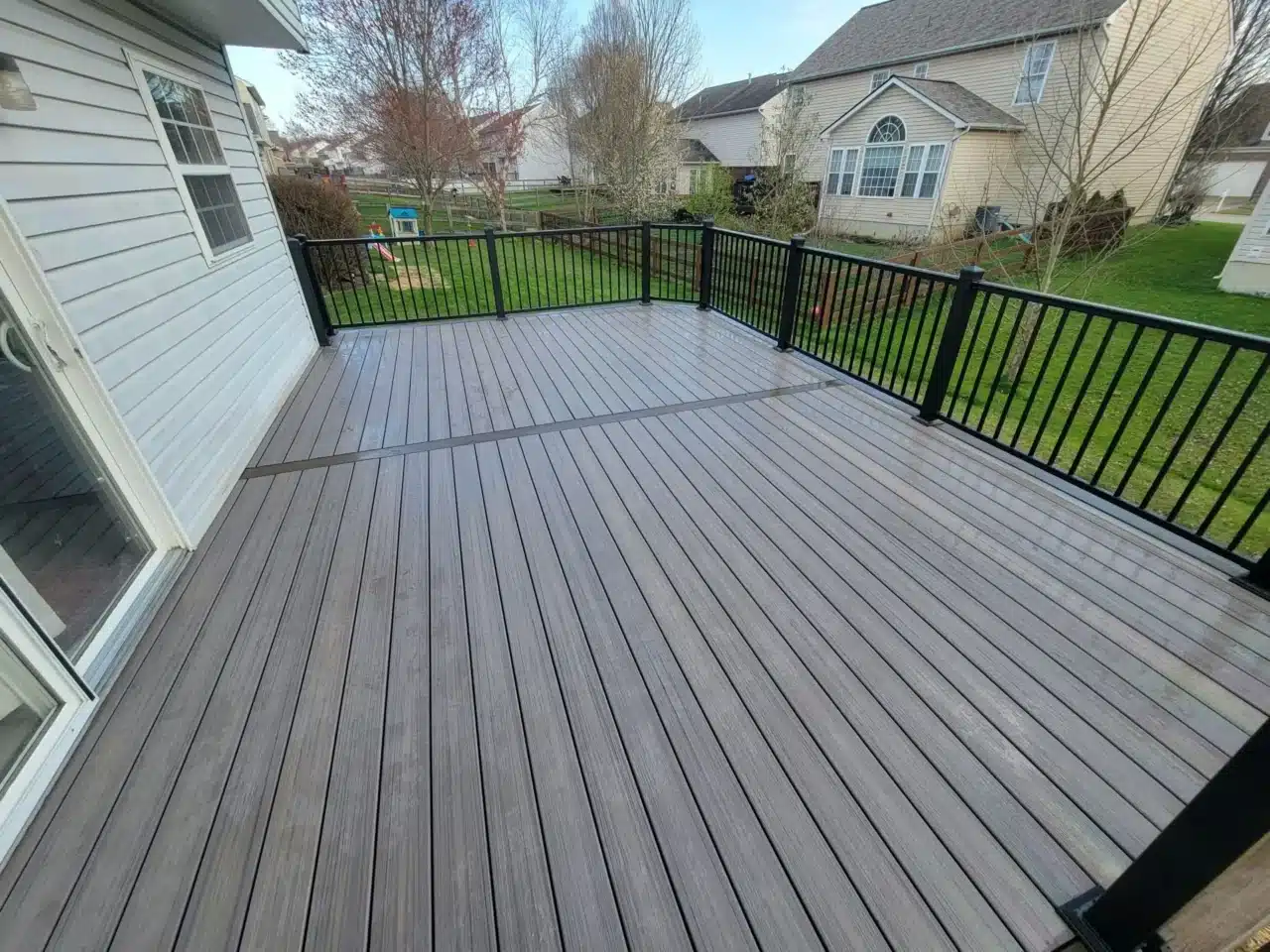 Mason deck contractor-built composite deck with metal railings A deck with composite decking and metal railings at the back of a house.
